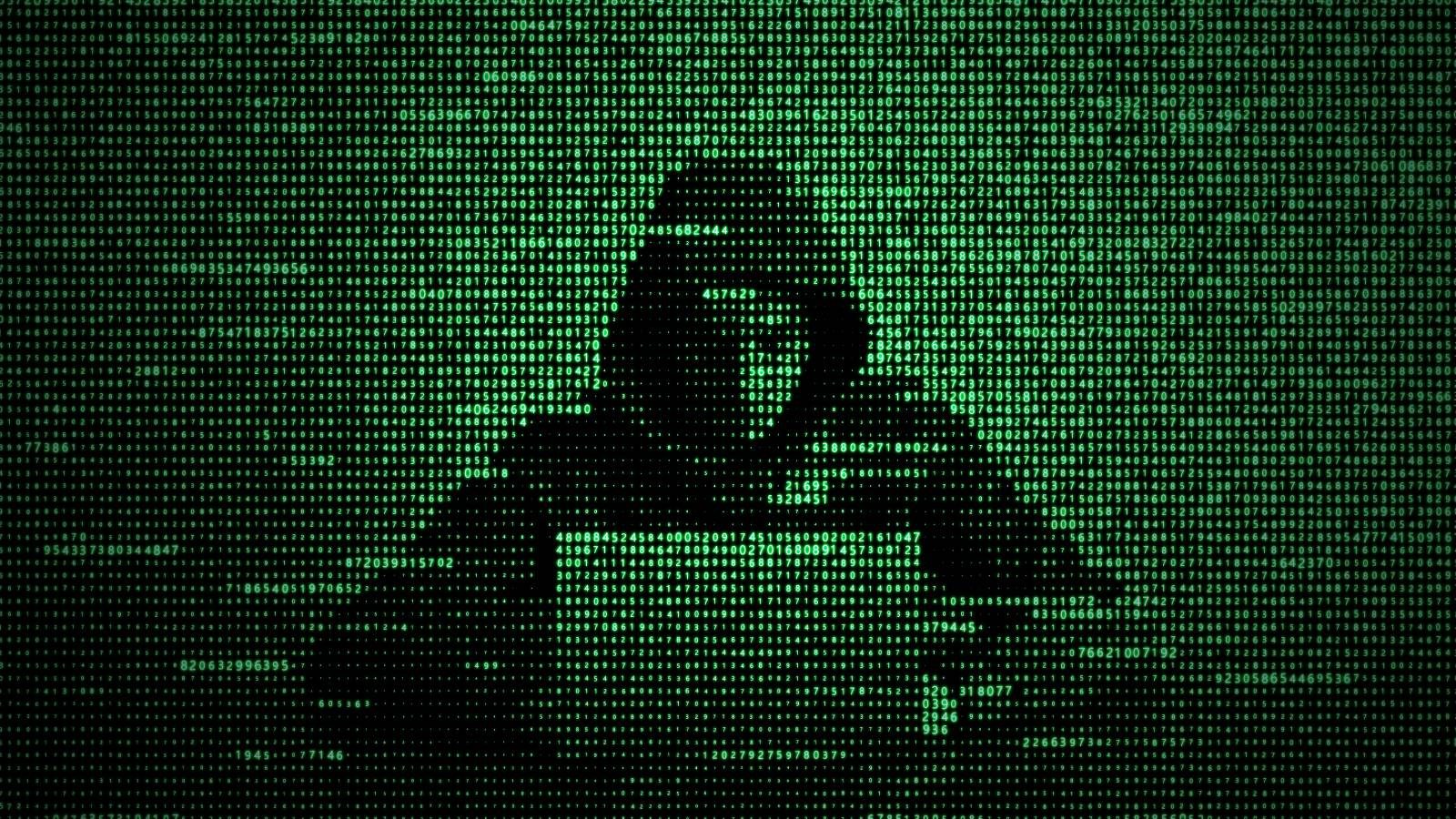 A hacker typing on a keyboard behind a screen of computer code